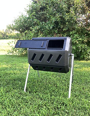 The FCMP Outdoor tumbling composter set up in a yard with its door open