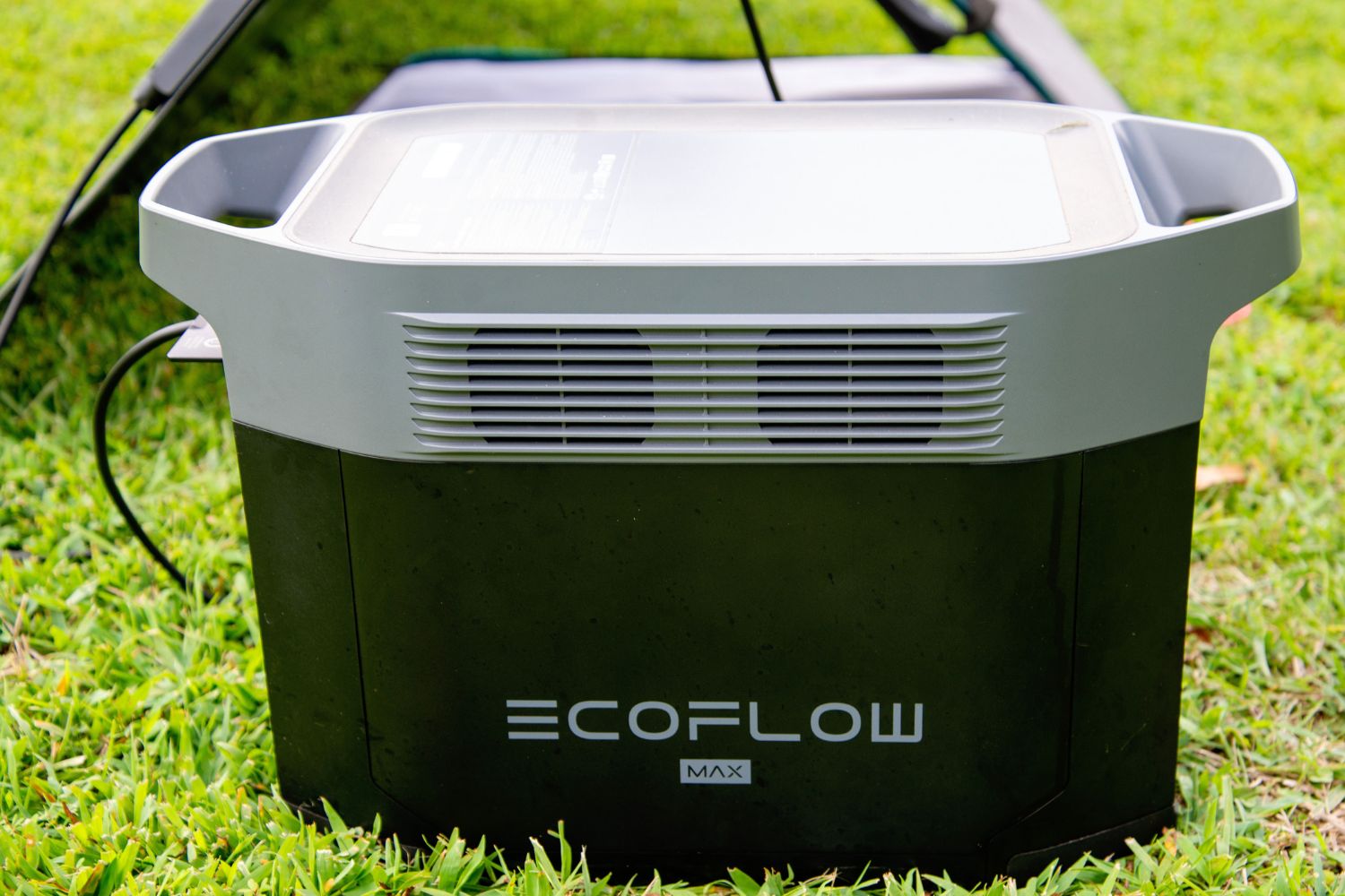 The EcoFlow Delta 2 Max solar generator next to its solar panel in a yard