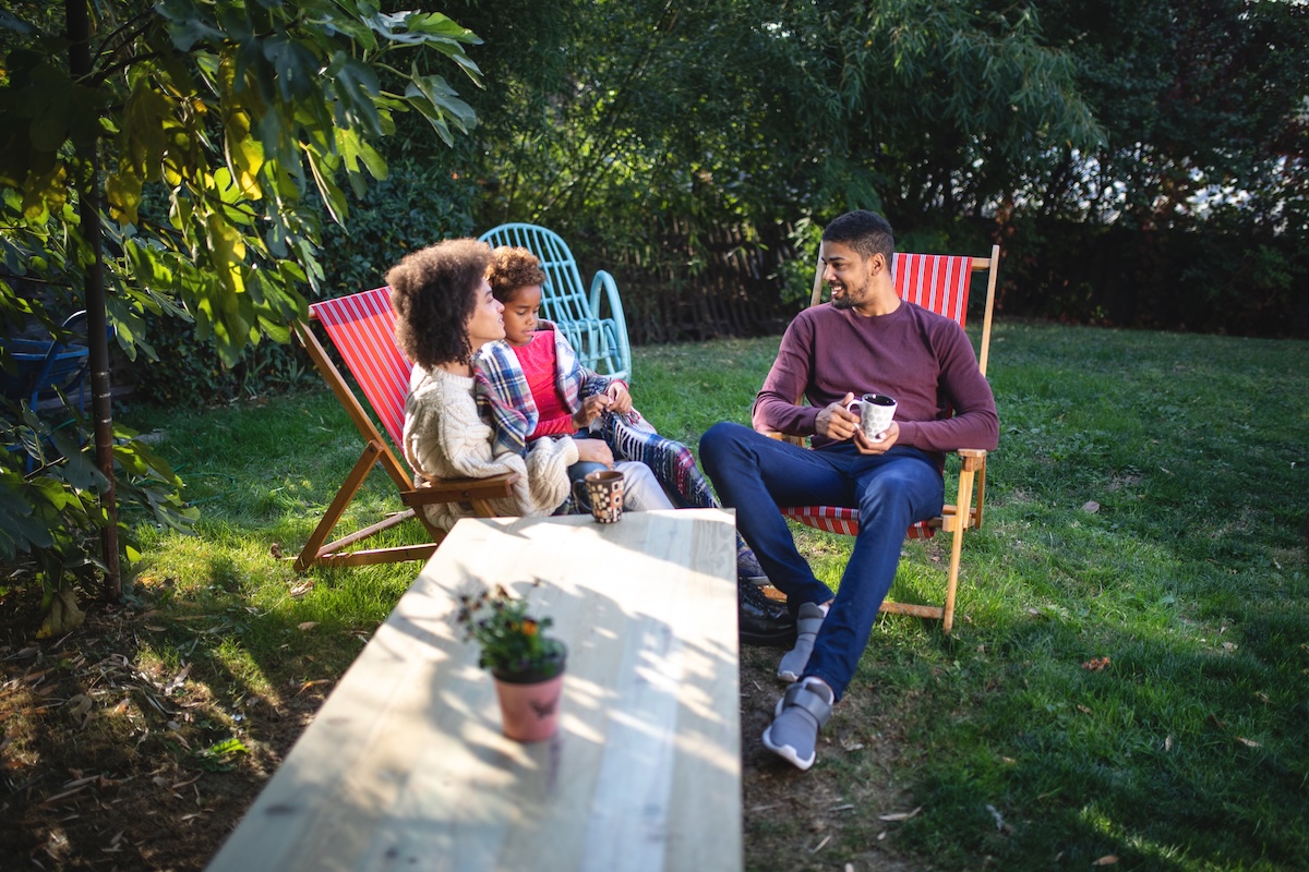 Backyard privacy ideas in a small outdoor space with family sitting in yard.