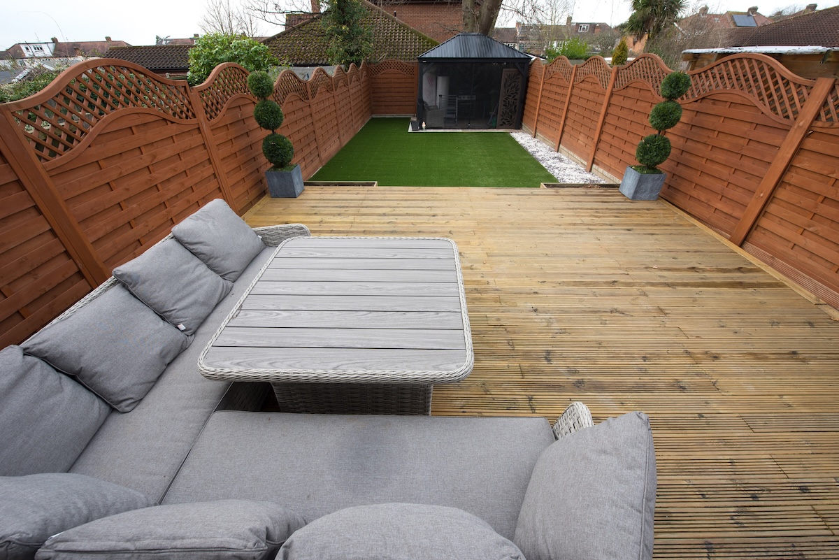 A small backyard with privacy fence and trellis on top of fence for more privacy.