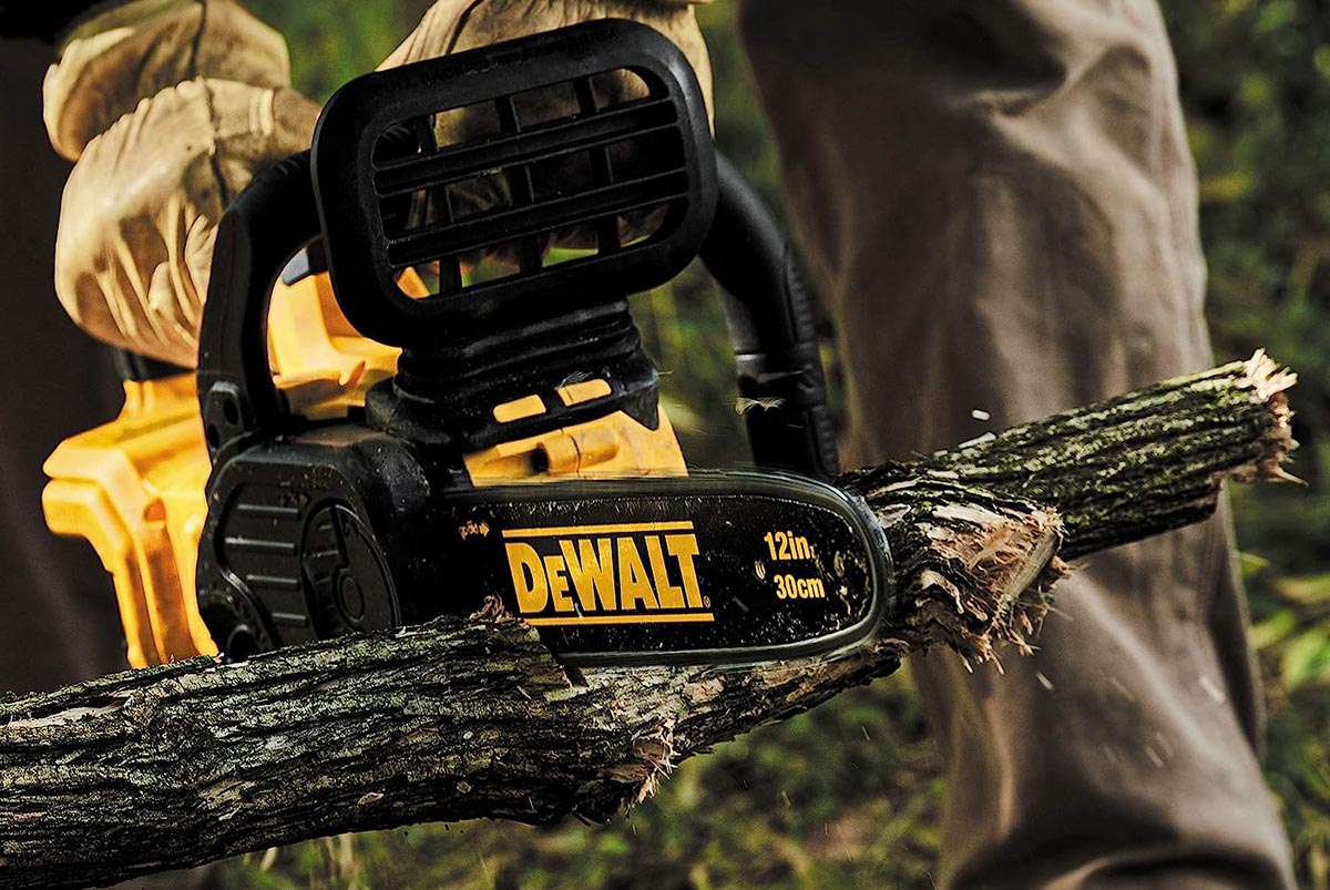 A person using the best DeWalt cordless chainsaw to cut a length of tree branch
