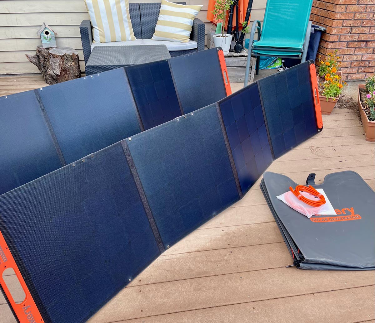 The Jackery 3000 Pro Solar Generator solar panels set up on a deck next to their carrying bags