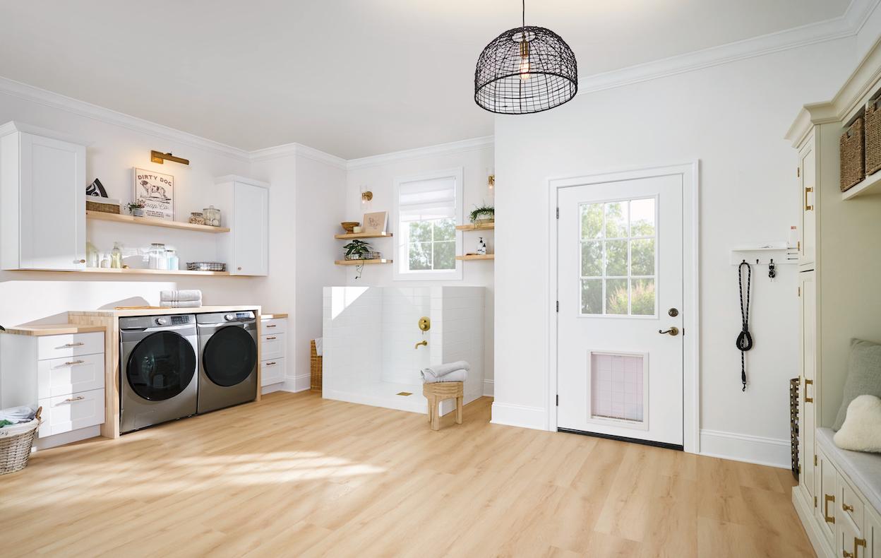 A modern, airy mudroom with light wood floors, a dog wash station, laundry, and more.