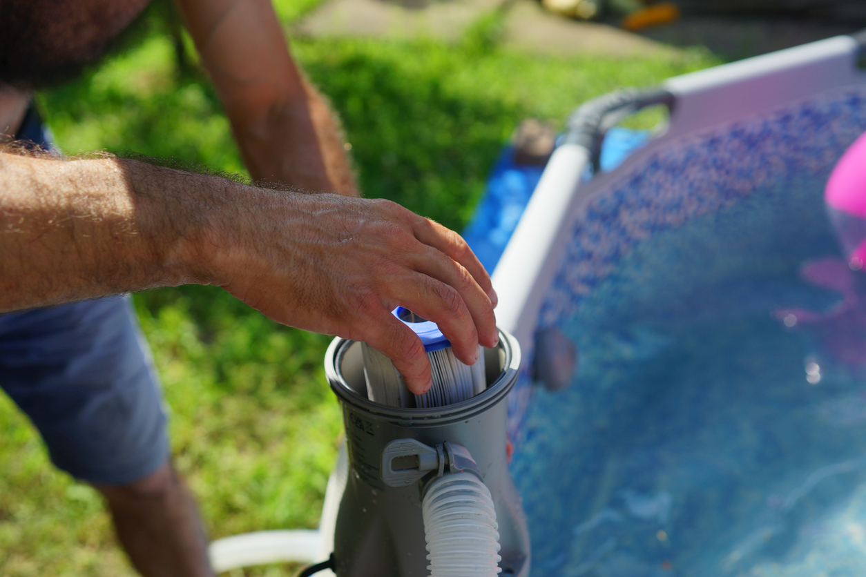 Side view of a new filter cartridge being installed into a small above-ground pool filter