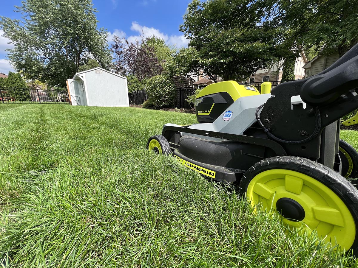 The Ryobi 21-inch self-propelled all-wheel-drive mower in action cutting a lawn with long and dense grass