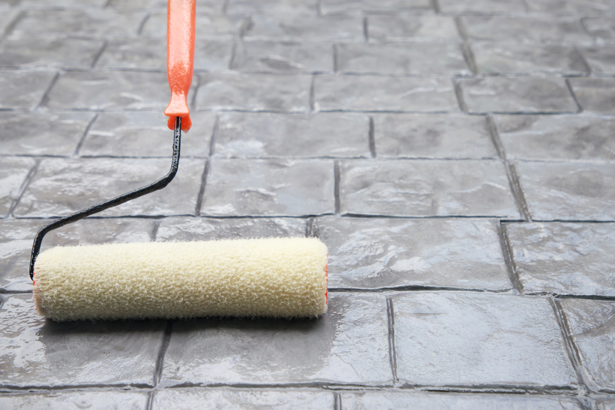 Using roller to apply a sealant or coating wet stamped concrete