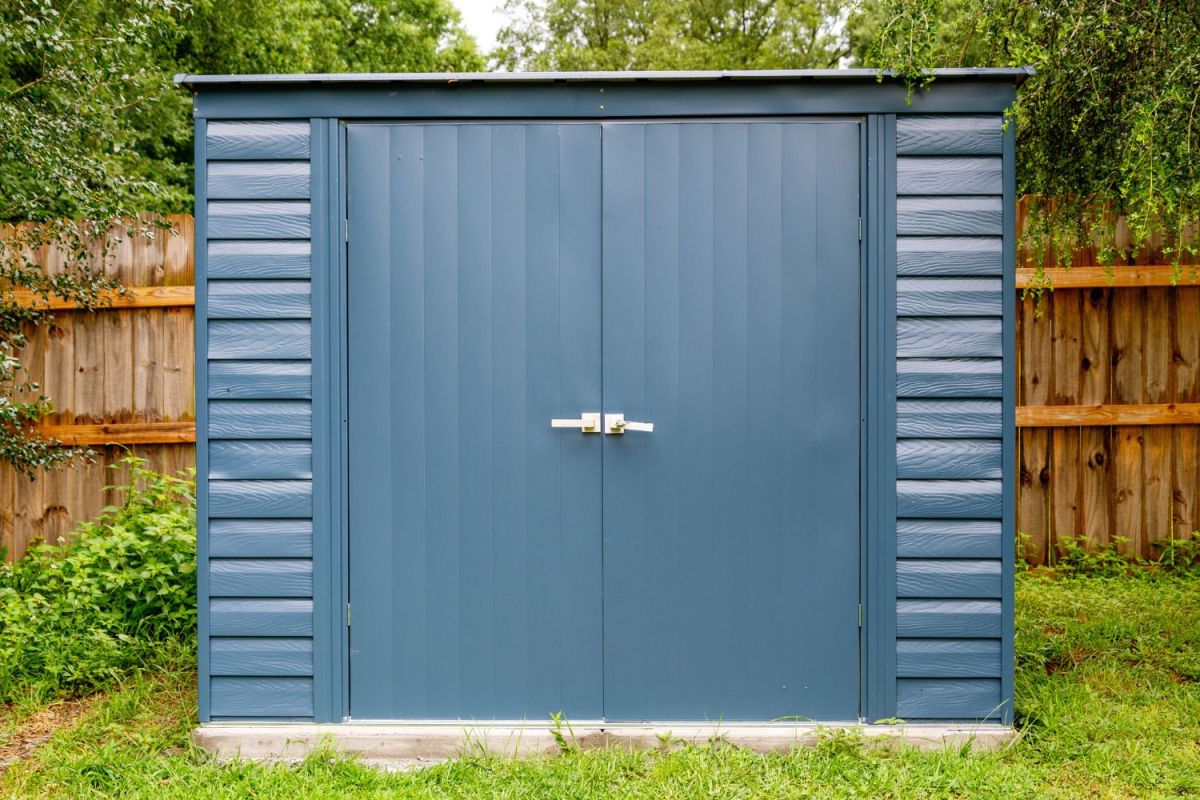 A front view of the ShelterLogic storage shed in a backyard