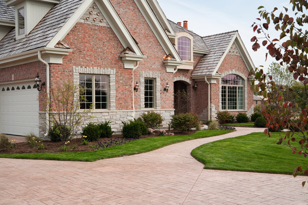 Brick home with a connected brick-style stamped concrete driveway and walkway