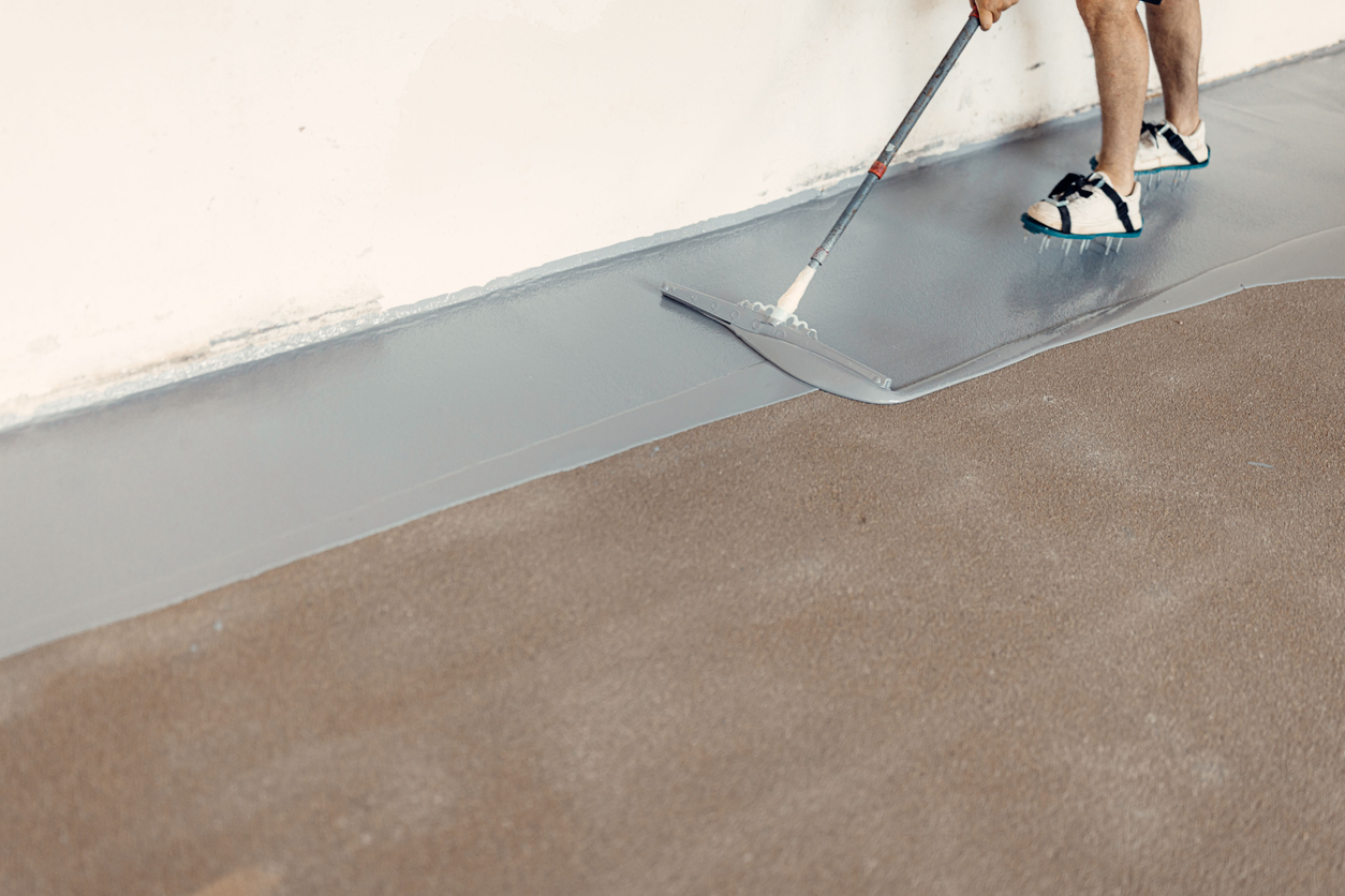 A person applying the best garage floor coatings option to a garage floor