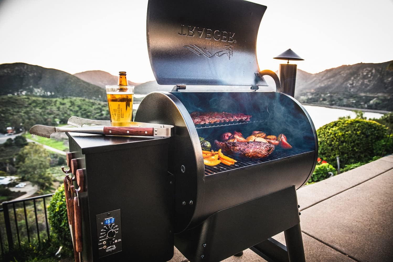The best pellet grills under $1,000 open to show two levels of meat and vegetables being grilled