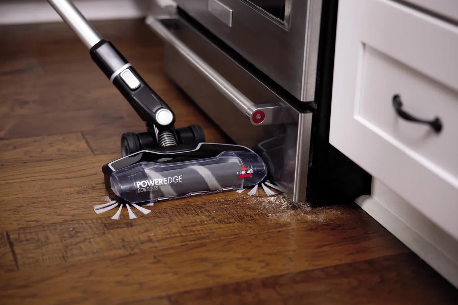The best cordless vacuum for hardwood floors option vacuuming a hardwood floor next to an oven