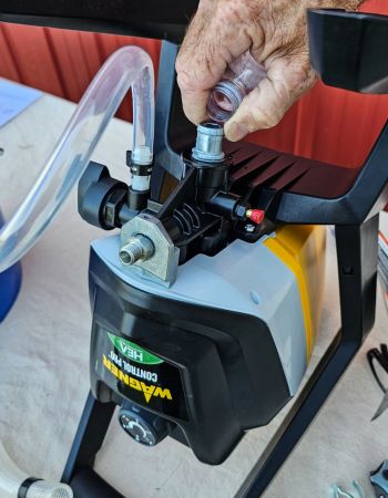 A person using water to prime the Wagner paint sprayer