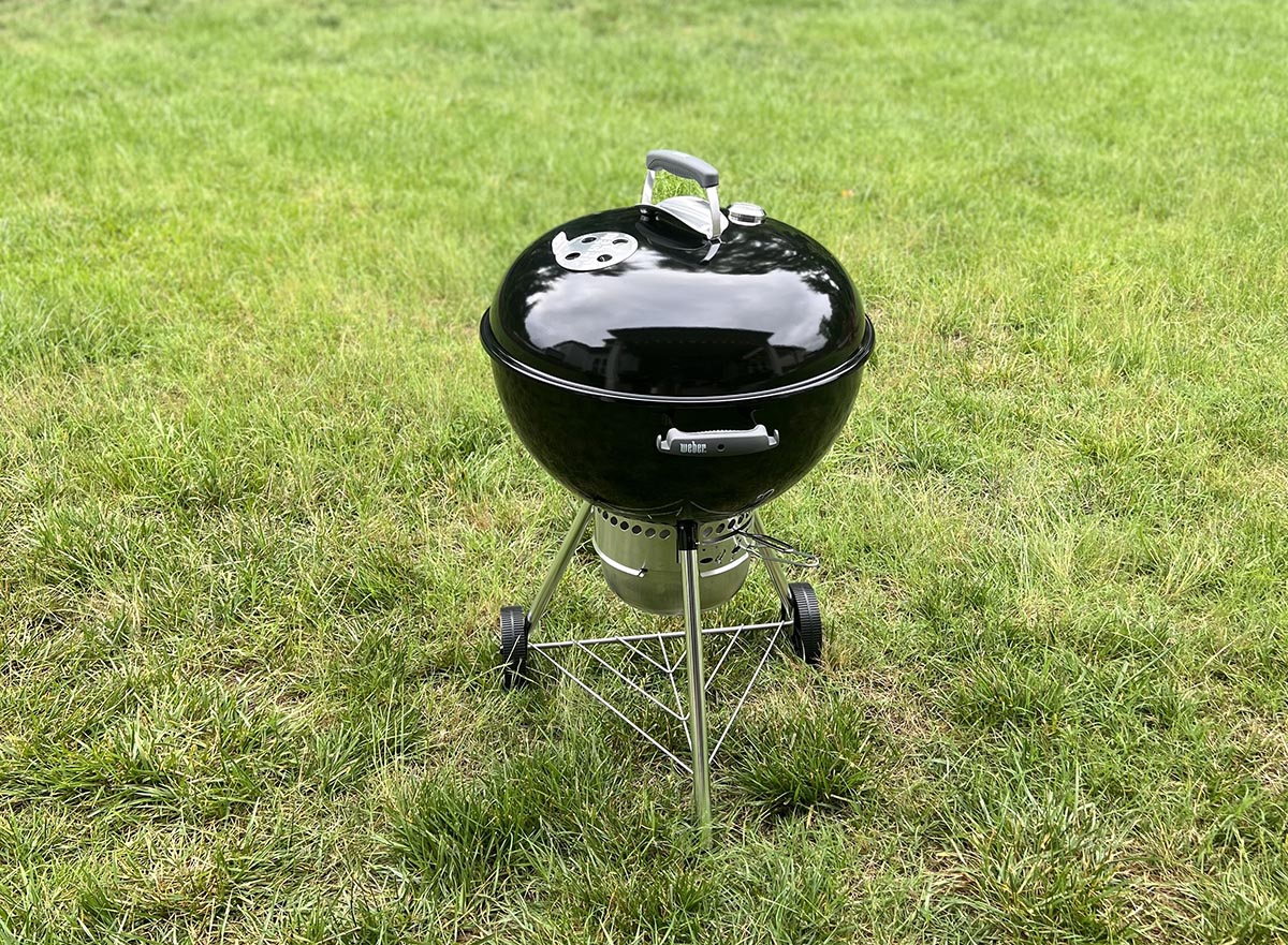 The Weber Original Kettle Premium charcoal grill set up for use in a yard