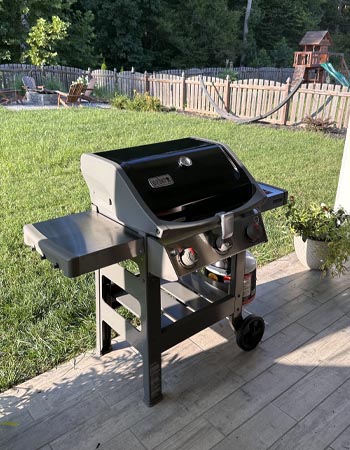 The Weber Spirit II E-310 Gas Grill ready to use on a back patio