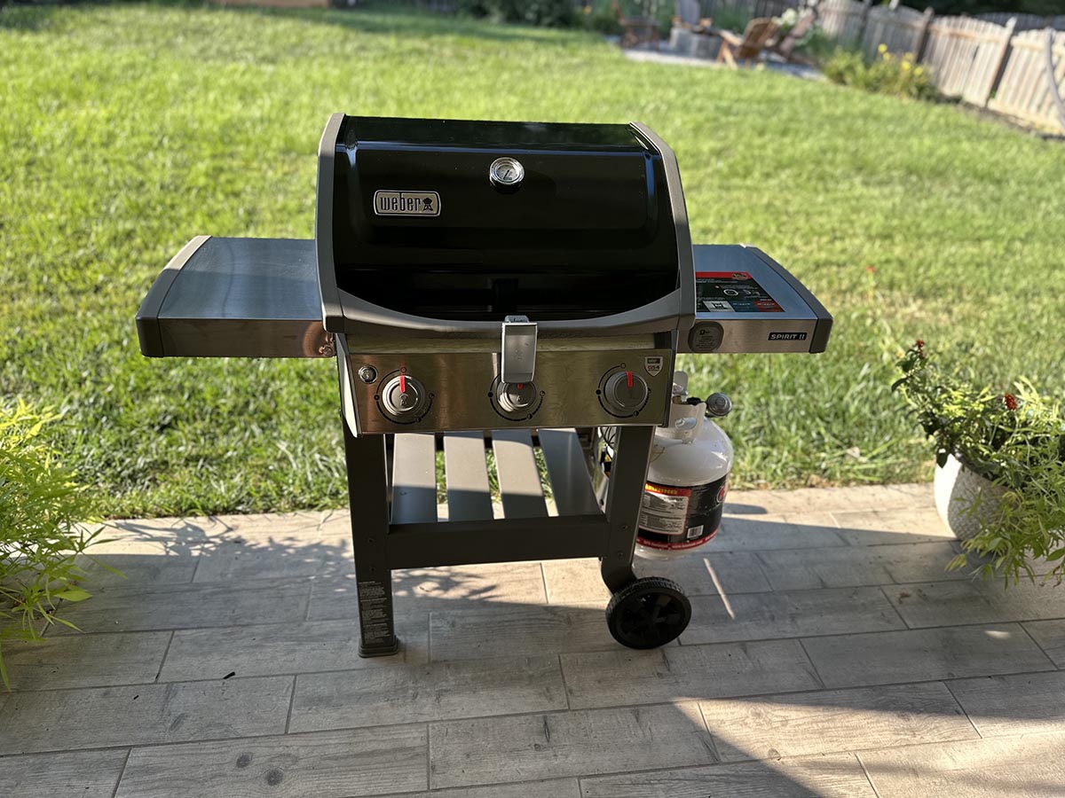 The Weber Spirit II E-310 Gas Grill ready to use on a back patio