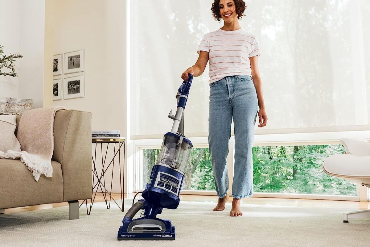 A person using the best vacuum under 200 option to clean a large area rug in a spacious living room