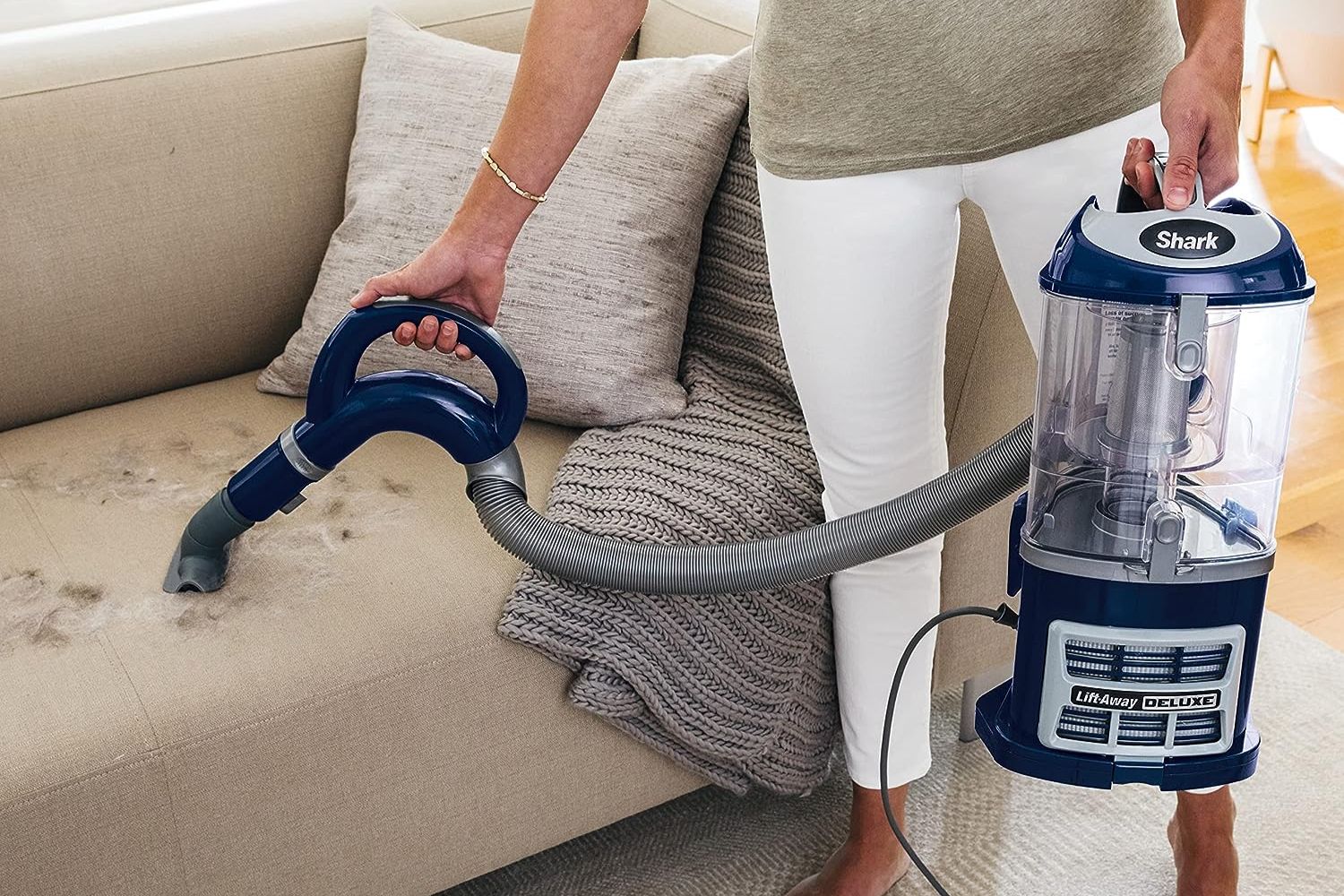 A person using the best vacuum under 200 option to vacuum pet hair from a couch