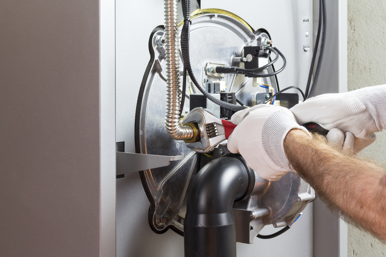 Person wearing gloves repairing condensing boiler