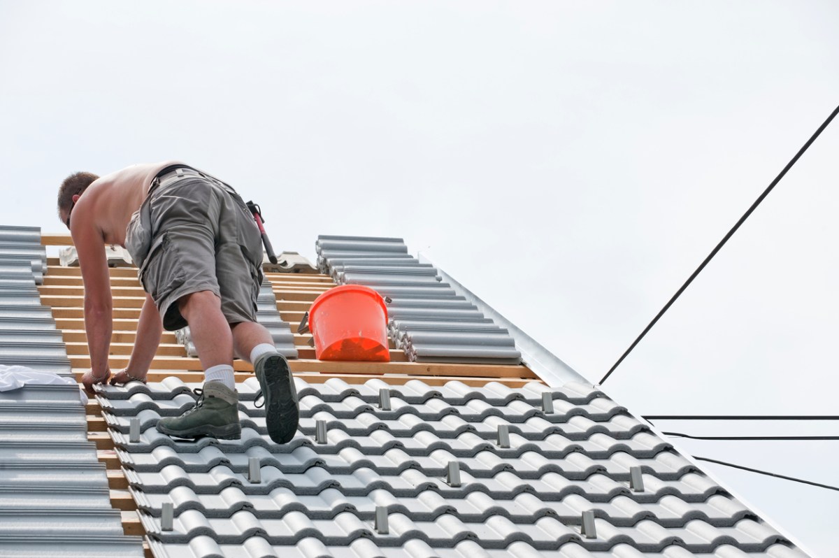 Roofer laying shingles on steep roof