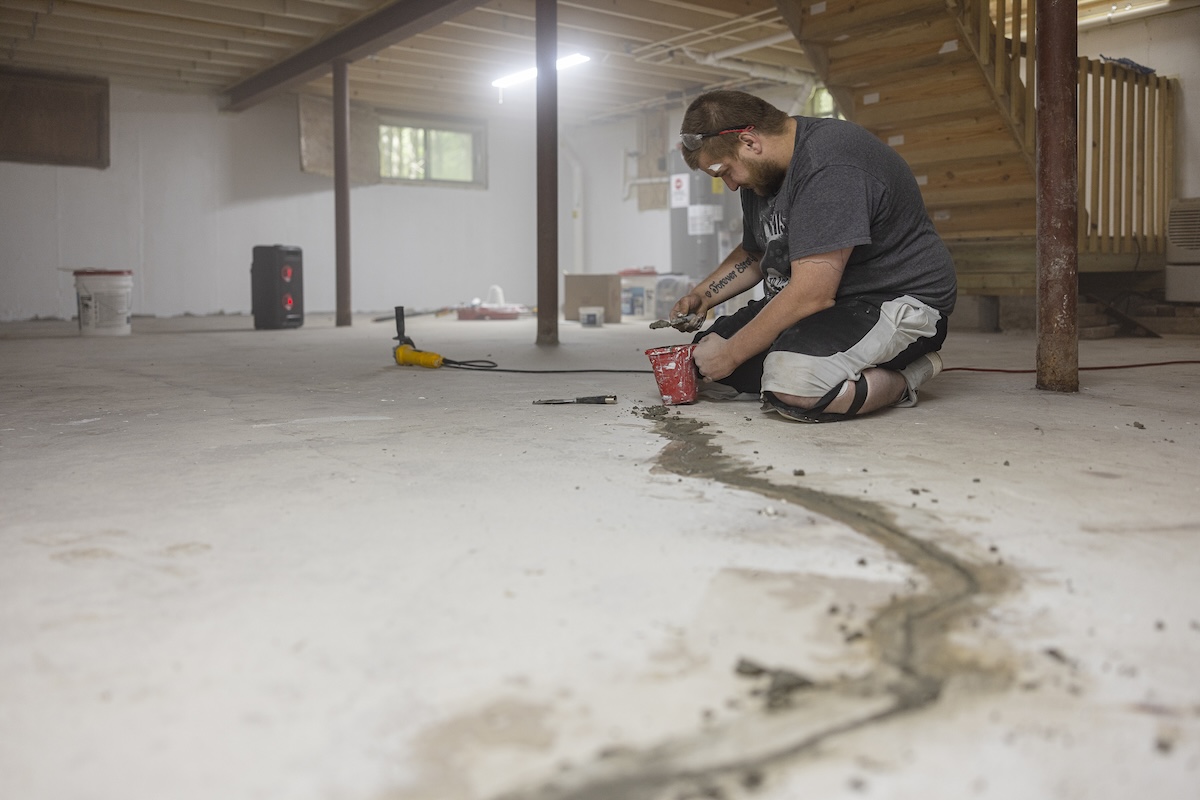A professional repairman repairs cracks in the foundation of a home basement.