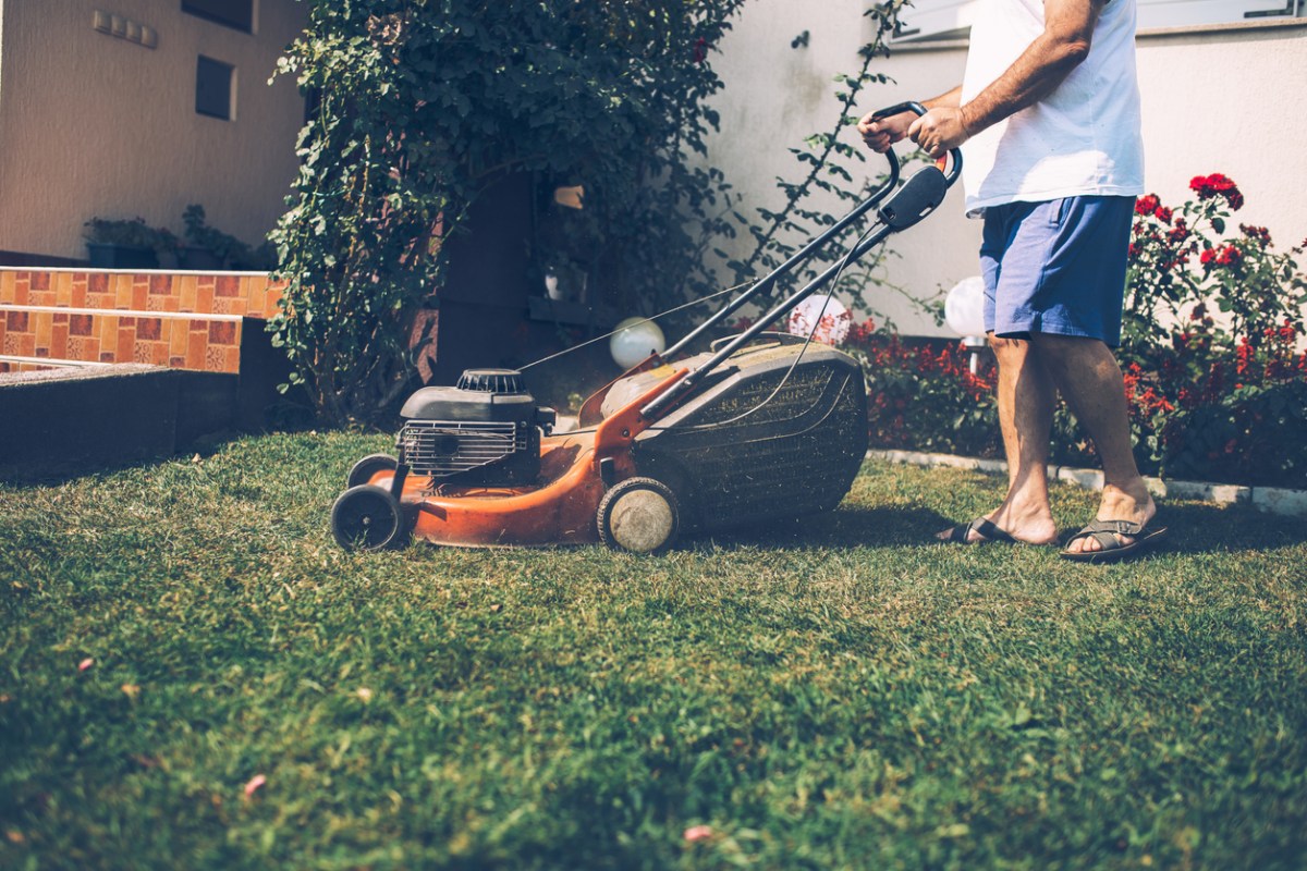 Close up of man in short and flip flops mowing the front lawn