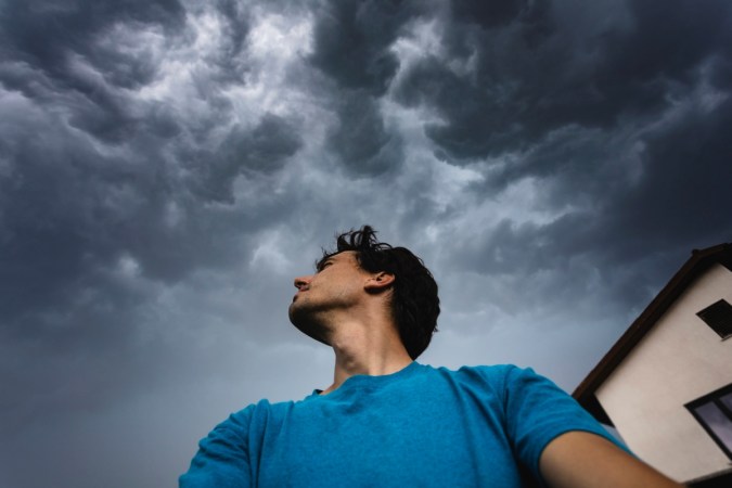 Man standing under dark clouds