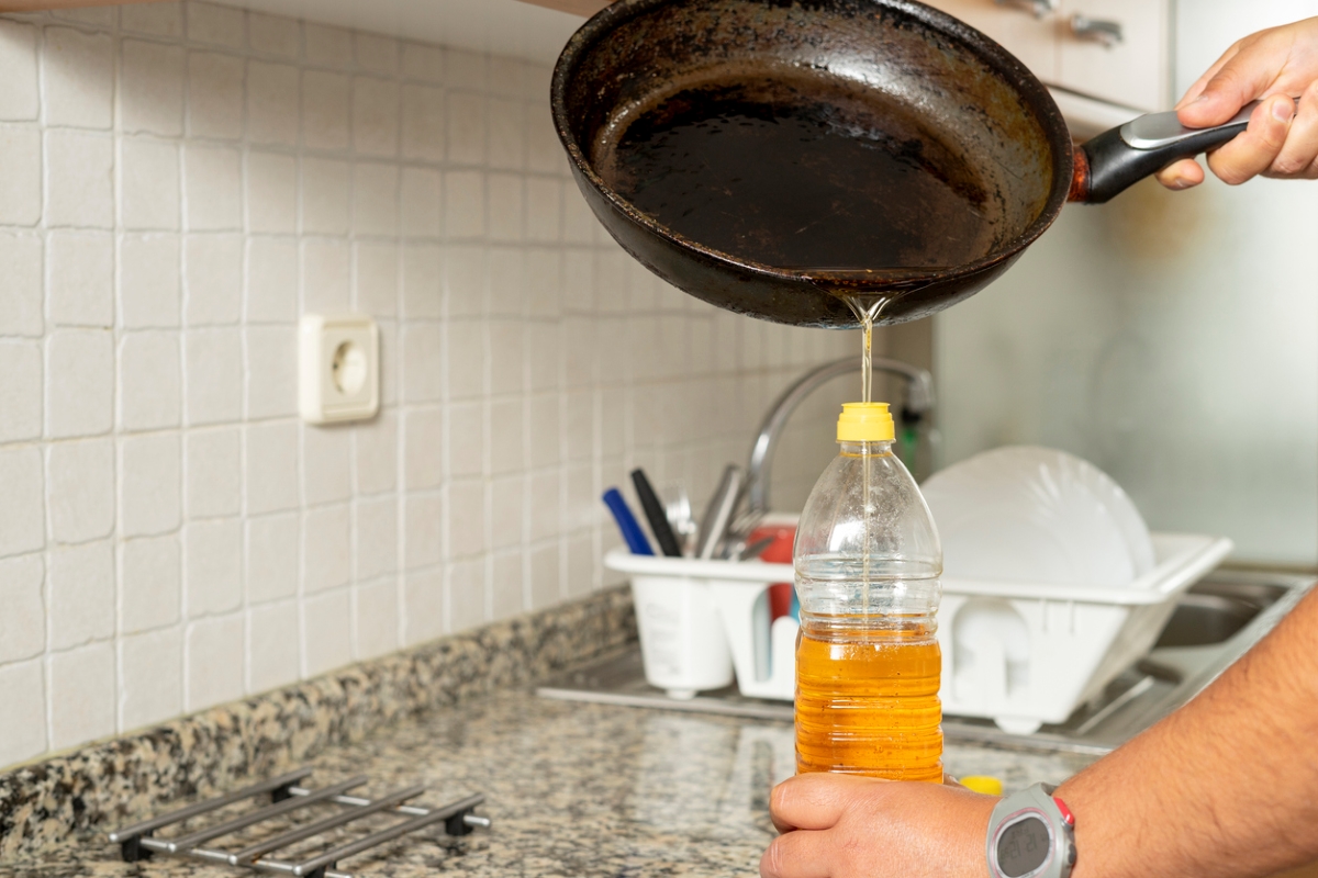 person pouring cooking oil in bottle