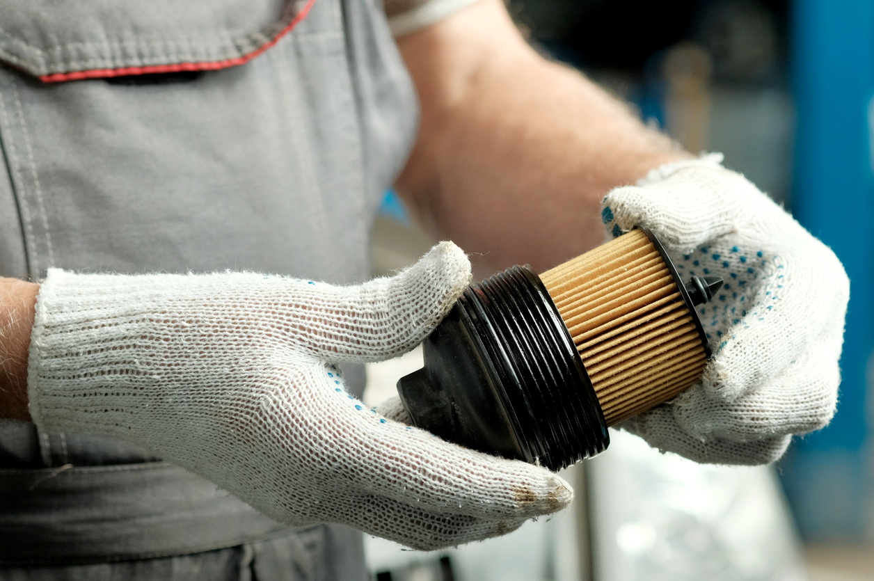 mechanic wearing gloves holding fuel filter