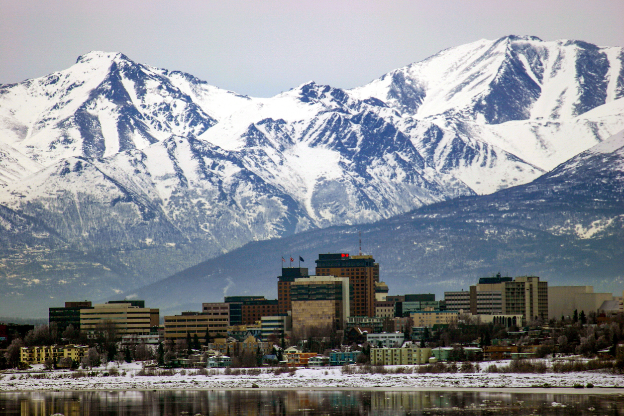 landscape view of lake in foreground and city of Anchorage Alaska with mountains in the background