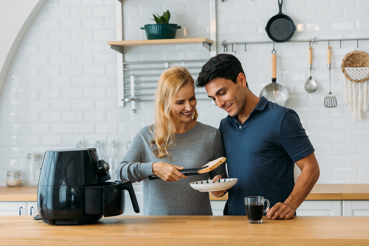 couple in kitchen using an air fryer