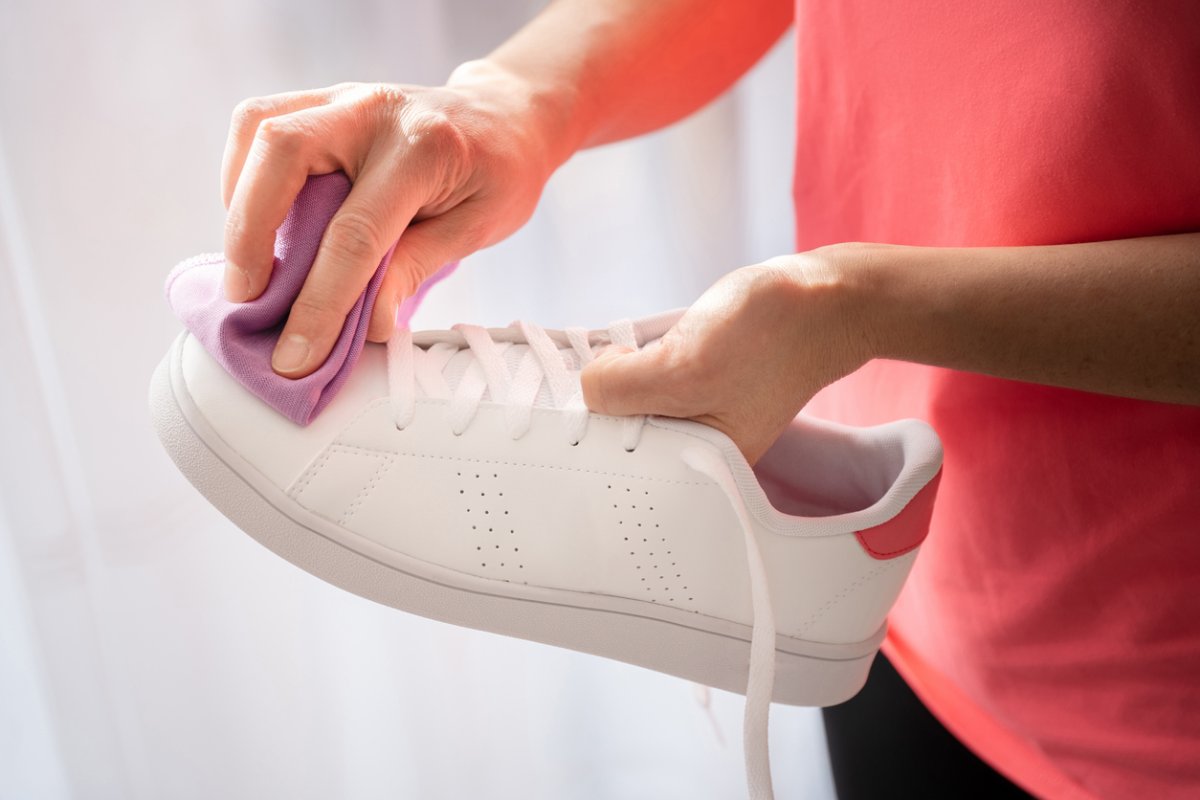 Woman cleaning white shoe with a purple microfiber cloth