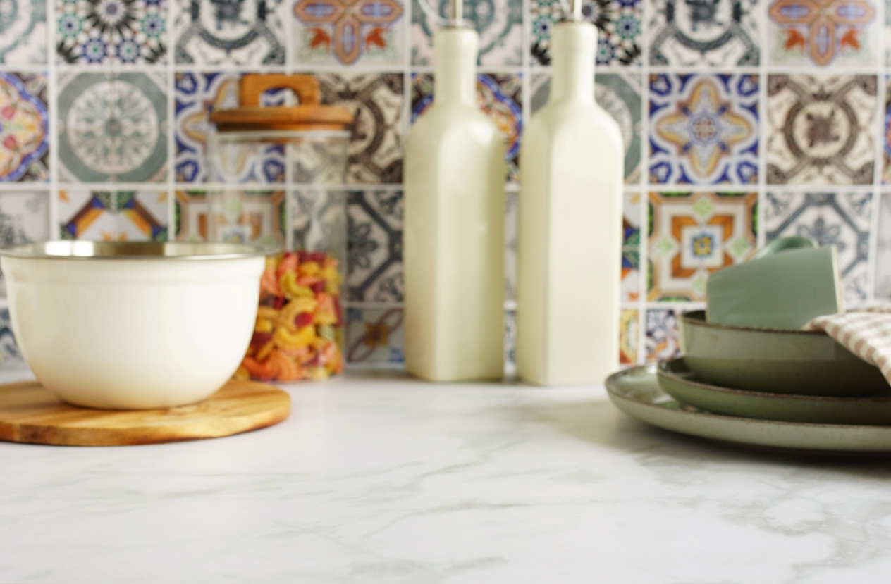 colorful-mosaic-backsplash-over-a-white-granite-kitchen-countertop-with-serveware