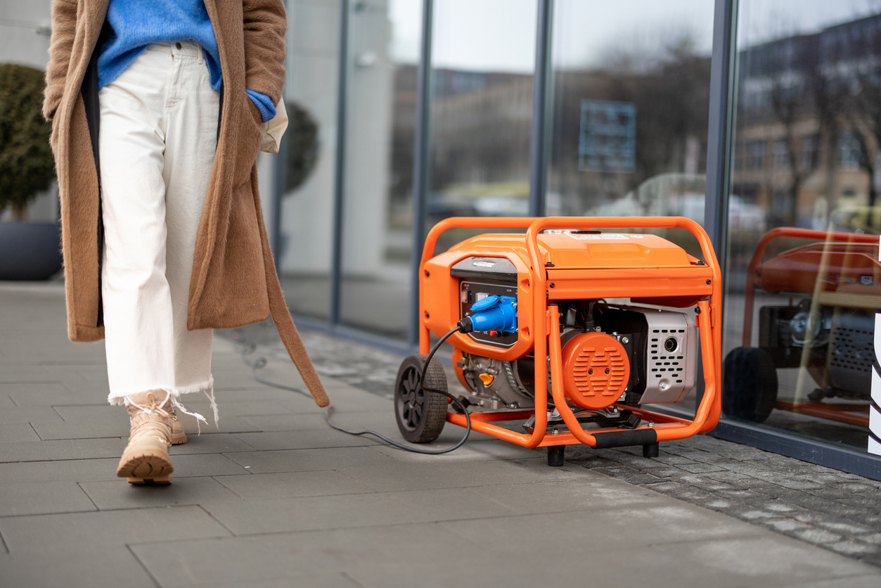 orange generator set up outside store as woman walks by on street