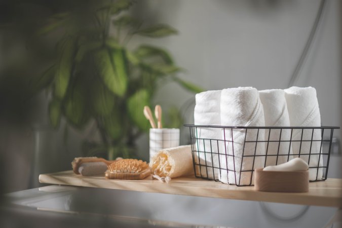 bathroom shelf with towels, loofah, brush, and tooth brushes