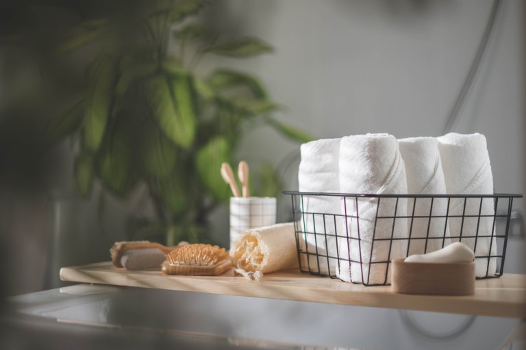 bathroom shelf with towels, loofah, brush, and tooth brushes