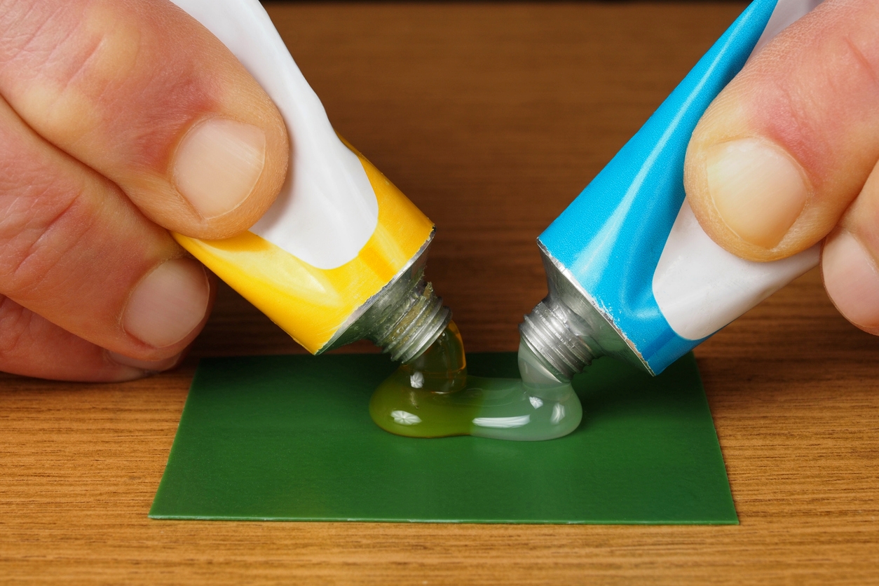 Two tubes of glue being squeezed