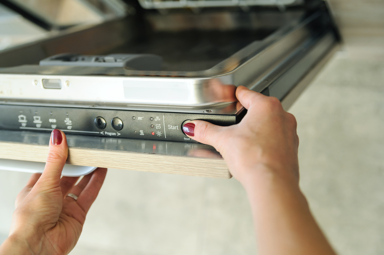 woman with red nails pressing buttons on dishwasher door to adjust wash settings