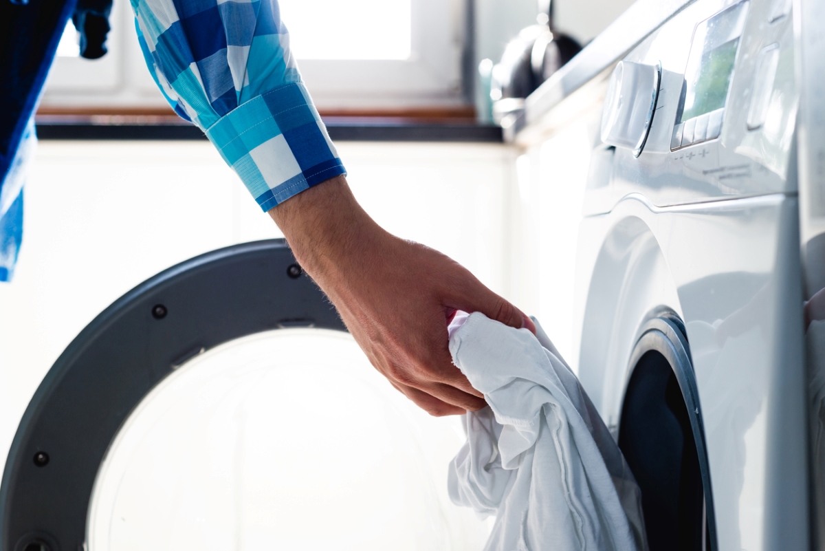 Person loading laundry into a front-load washing machine.