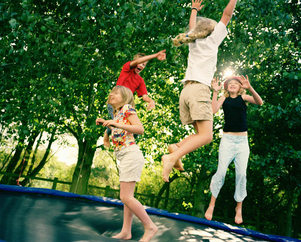 four kids jumping on an outdoor trampoline