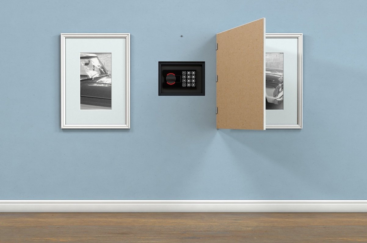 A closed hidden wall safe revealed behind a hanging framed picture on a flat blue wall in a house with shiny wooden floors - 3D render