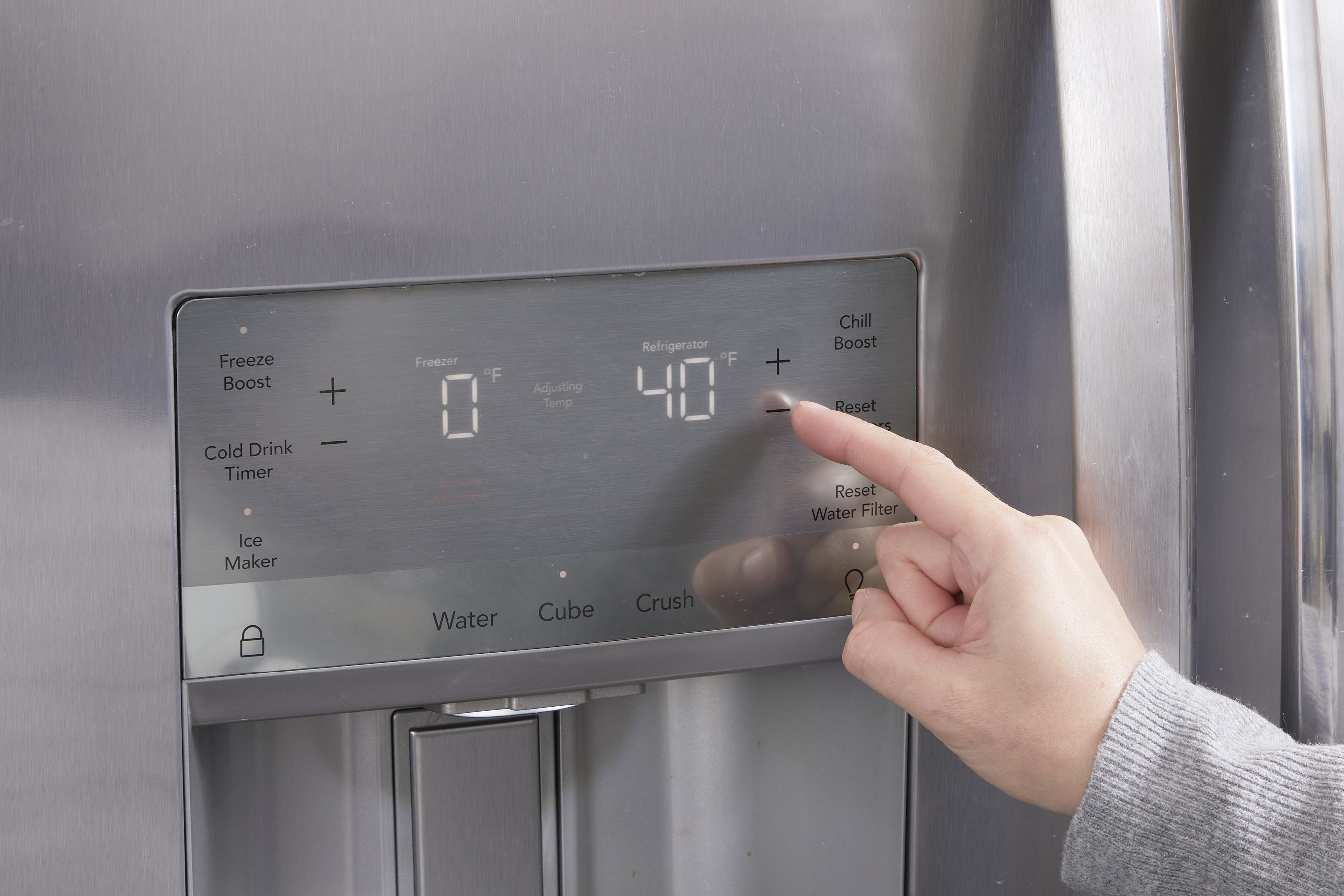 Woman sets the digital temperature on her fridge to 40 degrees F. 