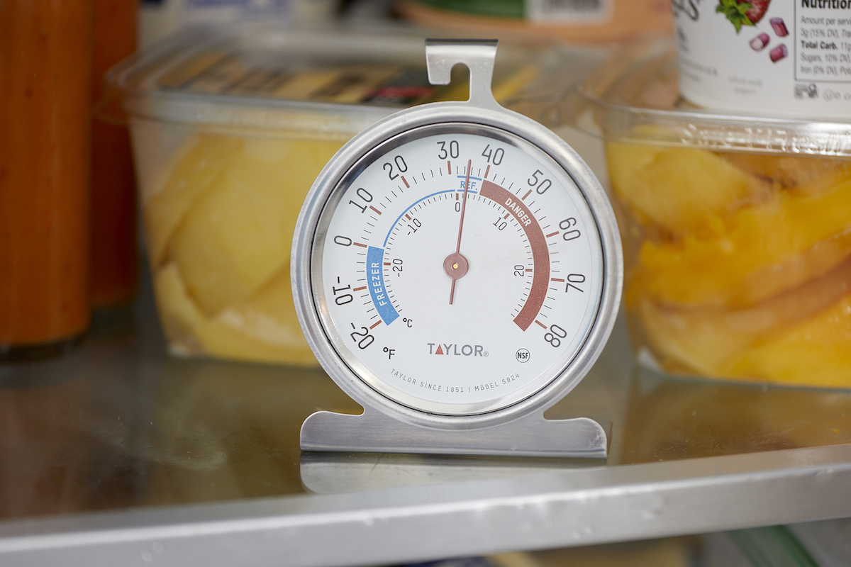 Close up of a refrigerator thermometer on a refrigerator shelf.