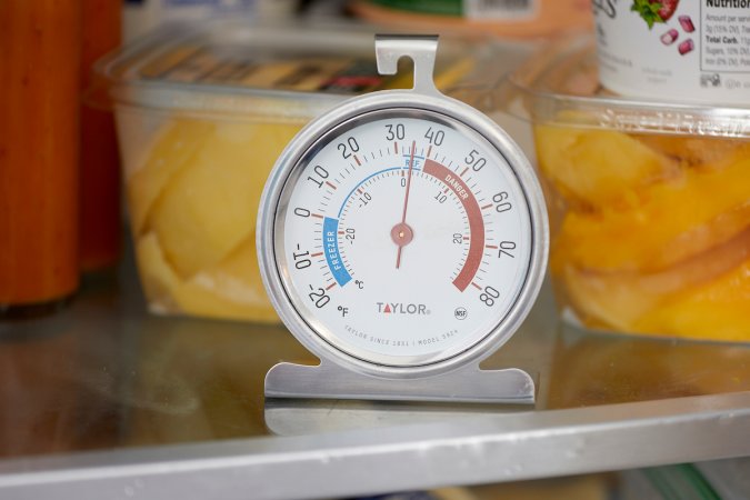 Close up of a refrigerator thermometer on a refrigerator shelf.