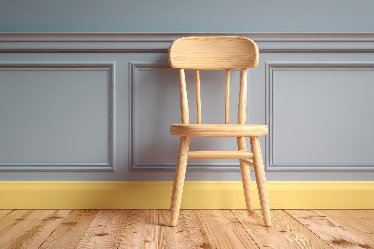 Wooden chair against pastel blue wall with chair rail molding.