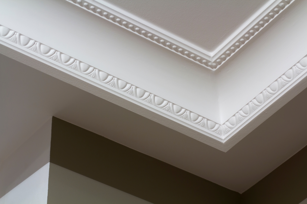 Ornamental white molding decor on ceiling of white room close-up detail.
