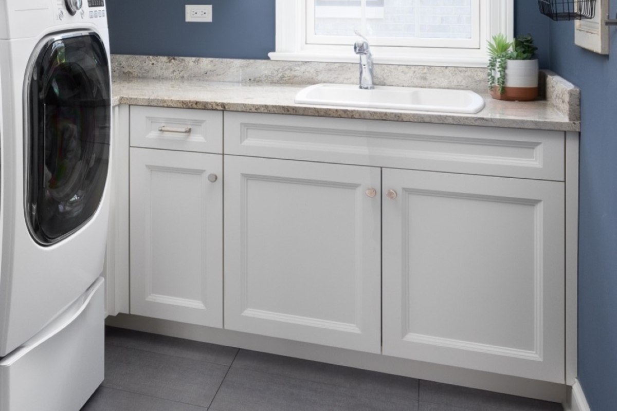 A laundry room with white cabinets and scribe trim.