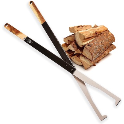 The Kabin Fire Tongs on a white background next to a pile of stacked wood.