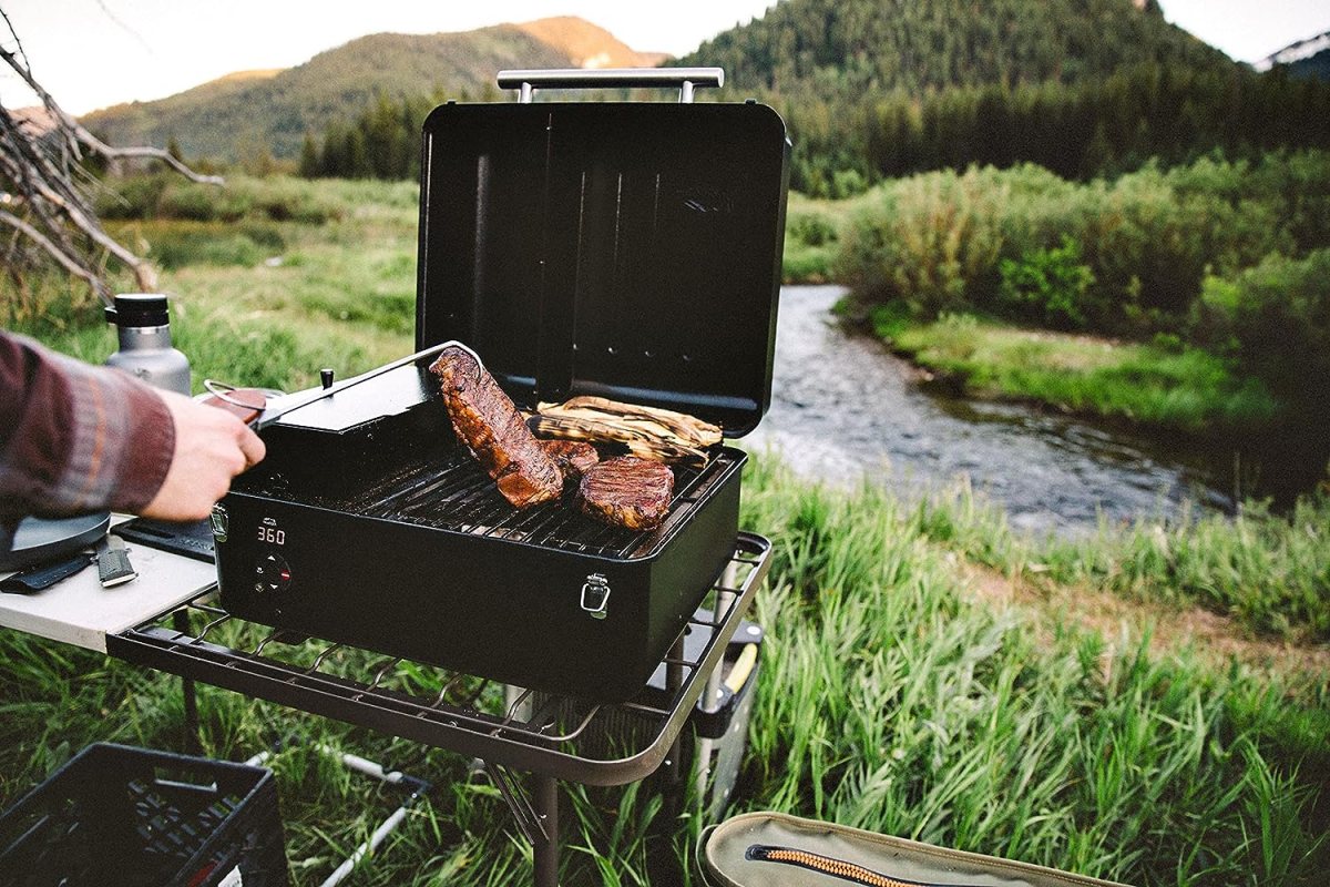 The best pellet grill under $500 in use grilling meat next to a river