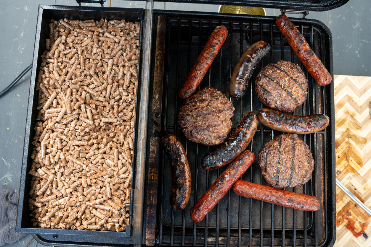 A top-down view of a full hopper next to meat grilling on the best pellet grill under $500
