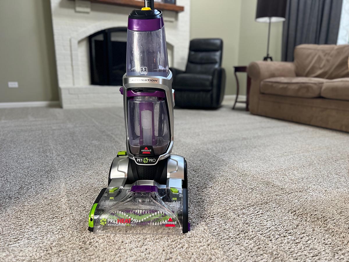 Bissell ProHeat 2X Revolution Pet Pro standing upright on freshly cleaned beige family room carpet.Review